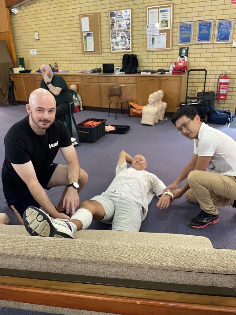 students bandaging leg at first aid course